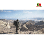 “Sam Porter Bridges carrying cargo across red desert in Death Stranding 2: On The Beach”